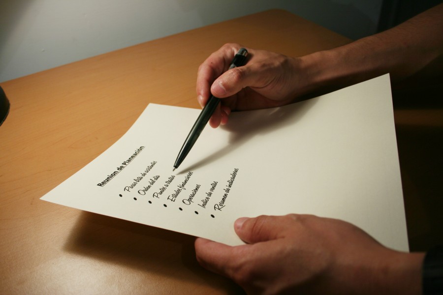 Two hands writing checklist on desk