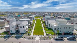 Aerial view of the Daybreak suburban neighborhood showcases modern houses from the Contempo Collection, neatly landscaped lawns, and a distant mountain backdrop.