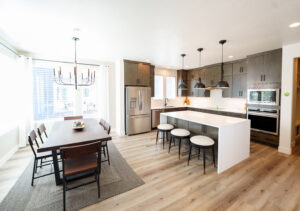 Bright and spacious modern kitchen featuring the Contempo Collection, complete with a sleek island and stainless steel appliances. The dining area showcases a dark wood table and chairs, perfect for enjoying breakfast at daybreak.