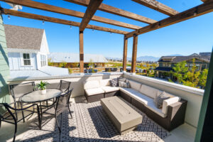 Experience the Rooftop Patio from the Contempo Collection, featuring a wooden pergola, a sleek white sectional sofa, and a glass table. Enjoy breathtaking mountain views as daylight turns to dusk in perfect harmony.