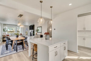 Modern open-concept kitchen and dining area with pendant lights, white cabinetry, and easy access to the finished basement.