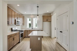 A modern kitchen with wooden cabinets, a center island, and stainless steel appliances under bright lighting offers a Grand Slam of style and functionality.