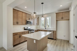 Modern kitchen with wooden cabinets, a center island, pendant lights, and stainless steel appliances offers a grand slam of design elements.