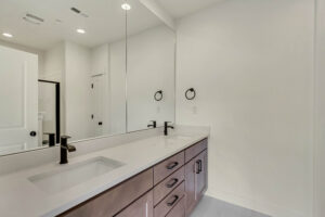 Modern bathroom with a long countertop, sink, large mirror, and dark fixtures that evoke the serene ambiance of Lake West.