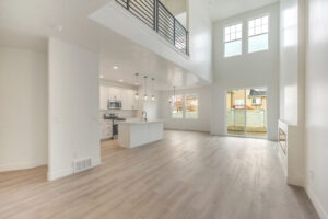 Spacious modern home interior with open kitchen, high ceilings, #16 large windows, and Blue Jay light wood floors.