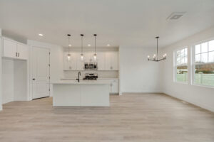 Modern kitchen with white cabinets, a Blue Jay island, pendant lights, and dining area adorned with a #16 chandelier.