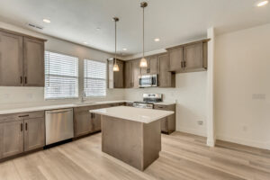 Modern kitchen with wooden cabinets, island, stainless steel appliances, and two pendant lights.