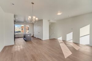 Spacious, unfurnished open-plan living area with wood flooring, kitchen island, and chandelier.