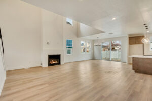 Open living space with light wood flooring, fireplace, large windows, and sliding glass doors leading to the Nightingale backyard.