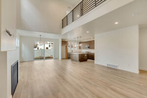 Spacious modern living area with high ceilings, open loft, wood flooring, and a kitchen adorned with Nightingale accents.