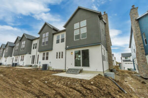 Nightingale townhouses under construction, boasting large windows with a cloudy sky backdrop.